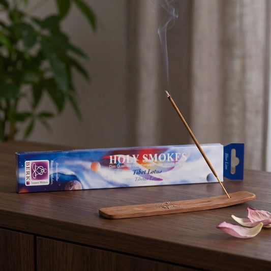 Tibet Lotus Räucherstäbchen Blue Line: glimmendes Räucherstäbchen mit feinem Rauch im Holzhalter, dahinter die Packung, auf einem Sideboard am Abend