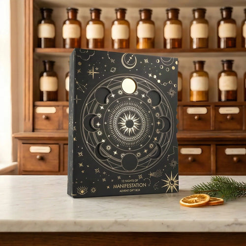 Adventskalender 12 Nights of Manifestation: schwarze Box mit goldenem Mondphasen-Kreis auf Marmortheke vor Apothekerschrank – Spirit of Gaia