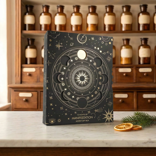 Adventskalender 12 Nights of Manifestation: schwarze Box mit goldenem Mondphasen-Kreis auf Marmortheke vor Apothekerschrank – Spirit of Gaia